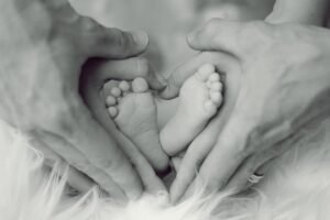 Father and mother's hands forming a love hear shape with infant's feet