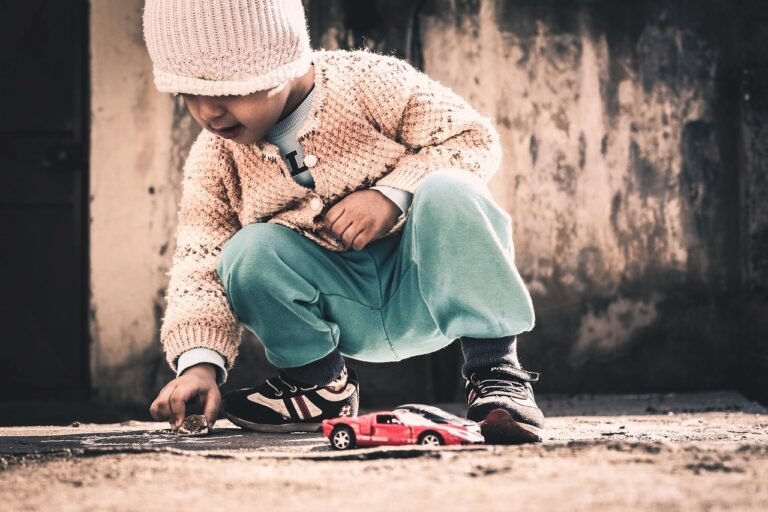 image of a child playing with a piece of rock, ignoring his toy cars
