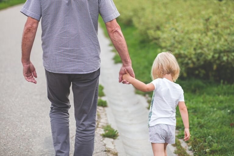 child holding her dad's hand, both going for a walk