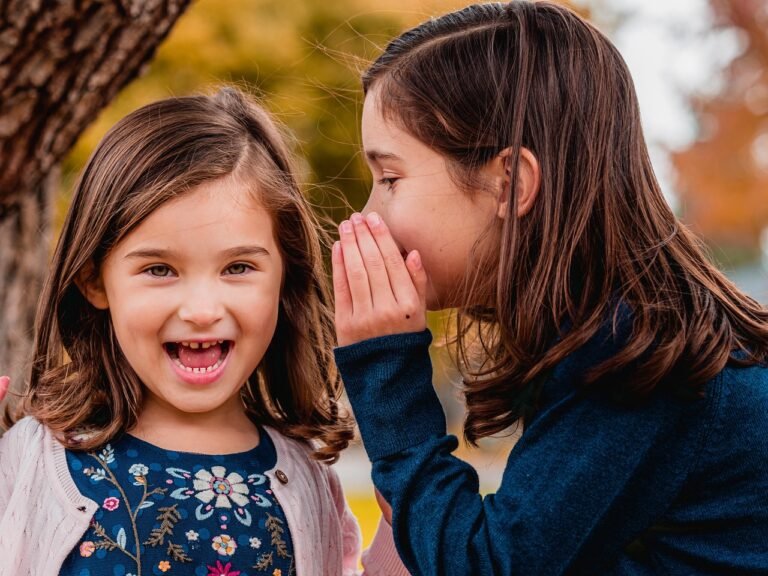 image of a child whispering words into her sister's ear